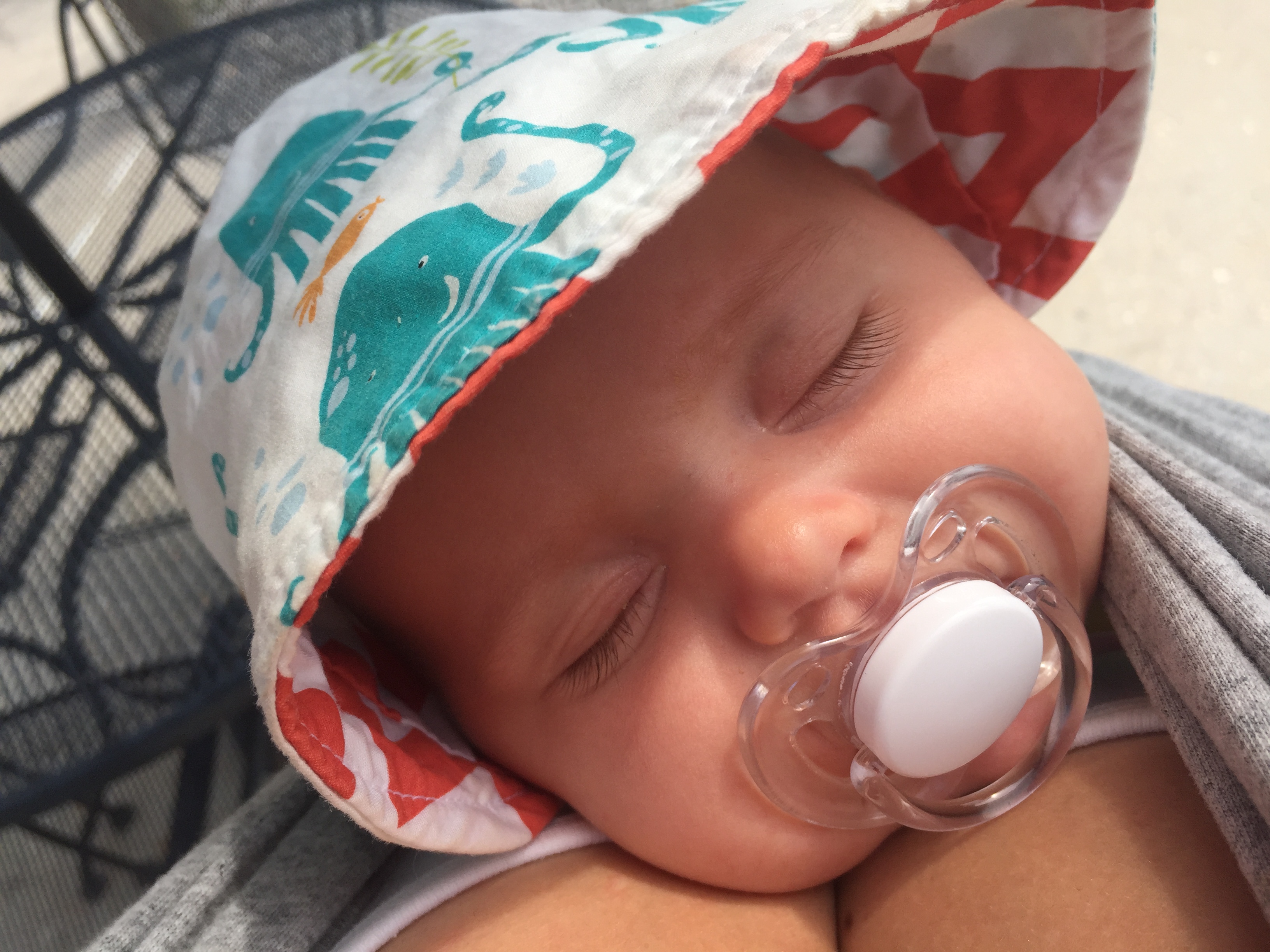 Baby sleeping with sun hat and pacifier