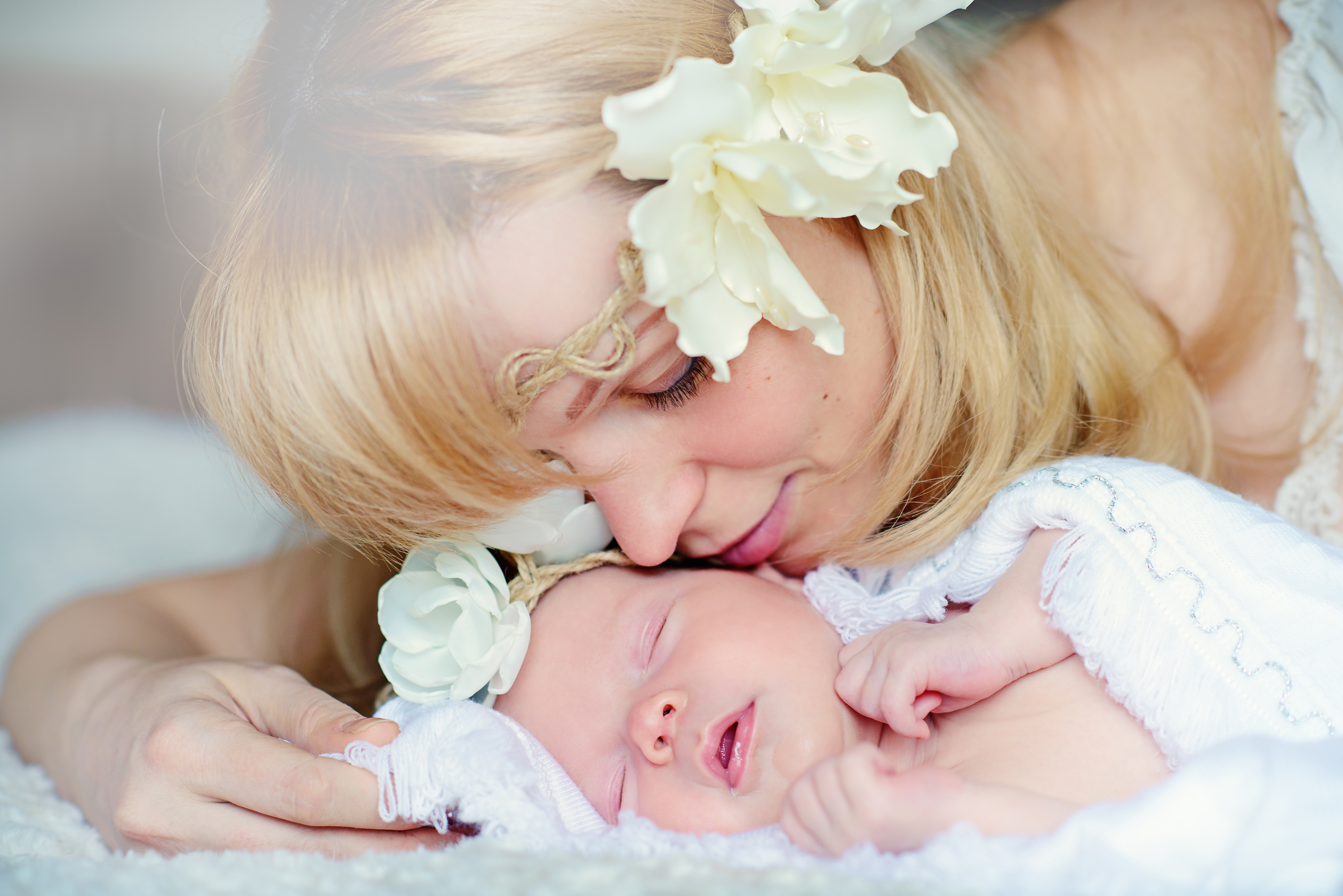 Mother kissing newborn with flower crown