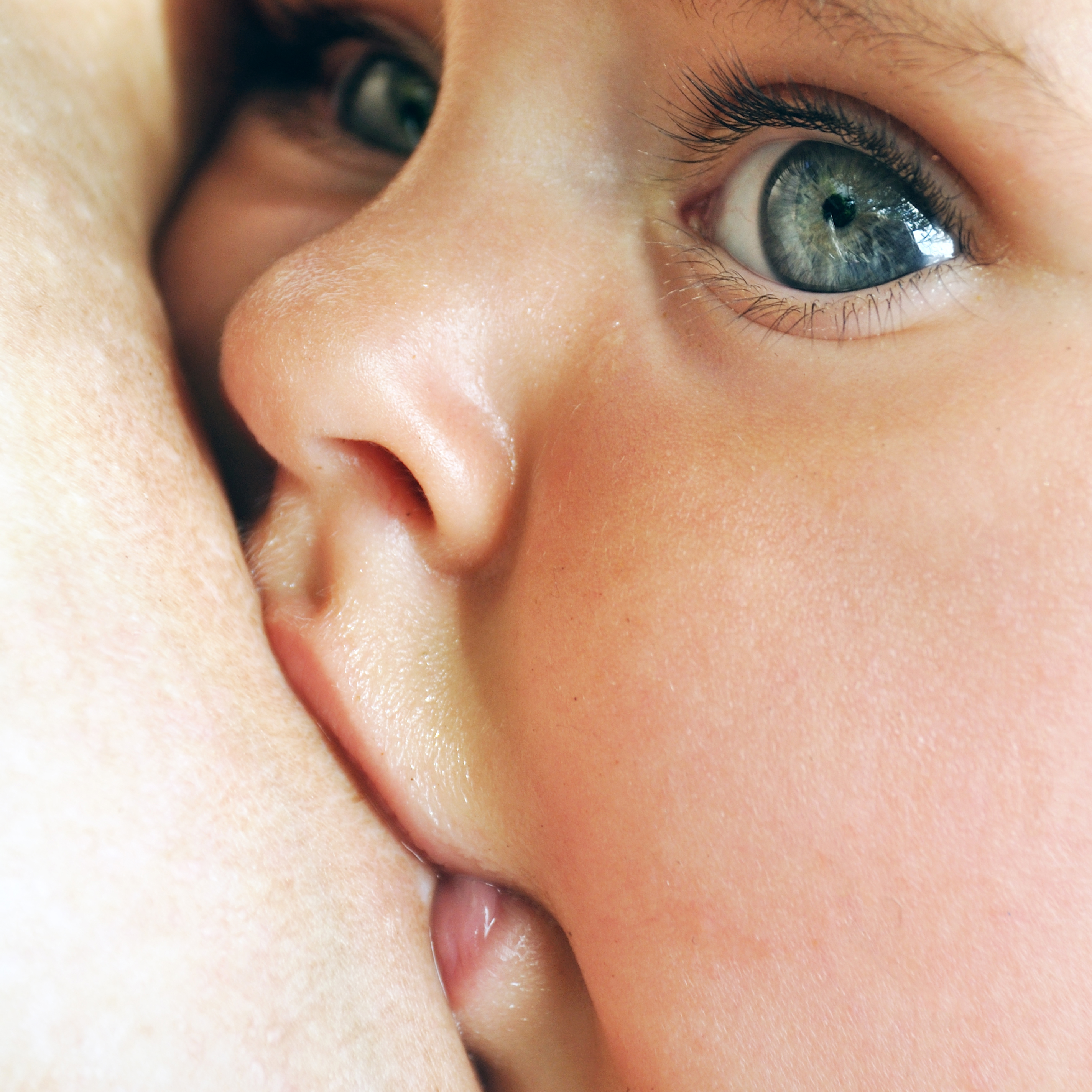Baby breastfeeding with big blue eyes